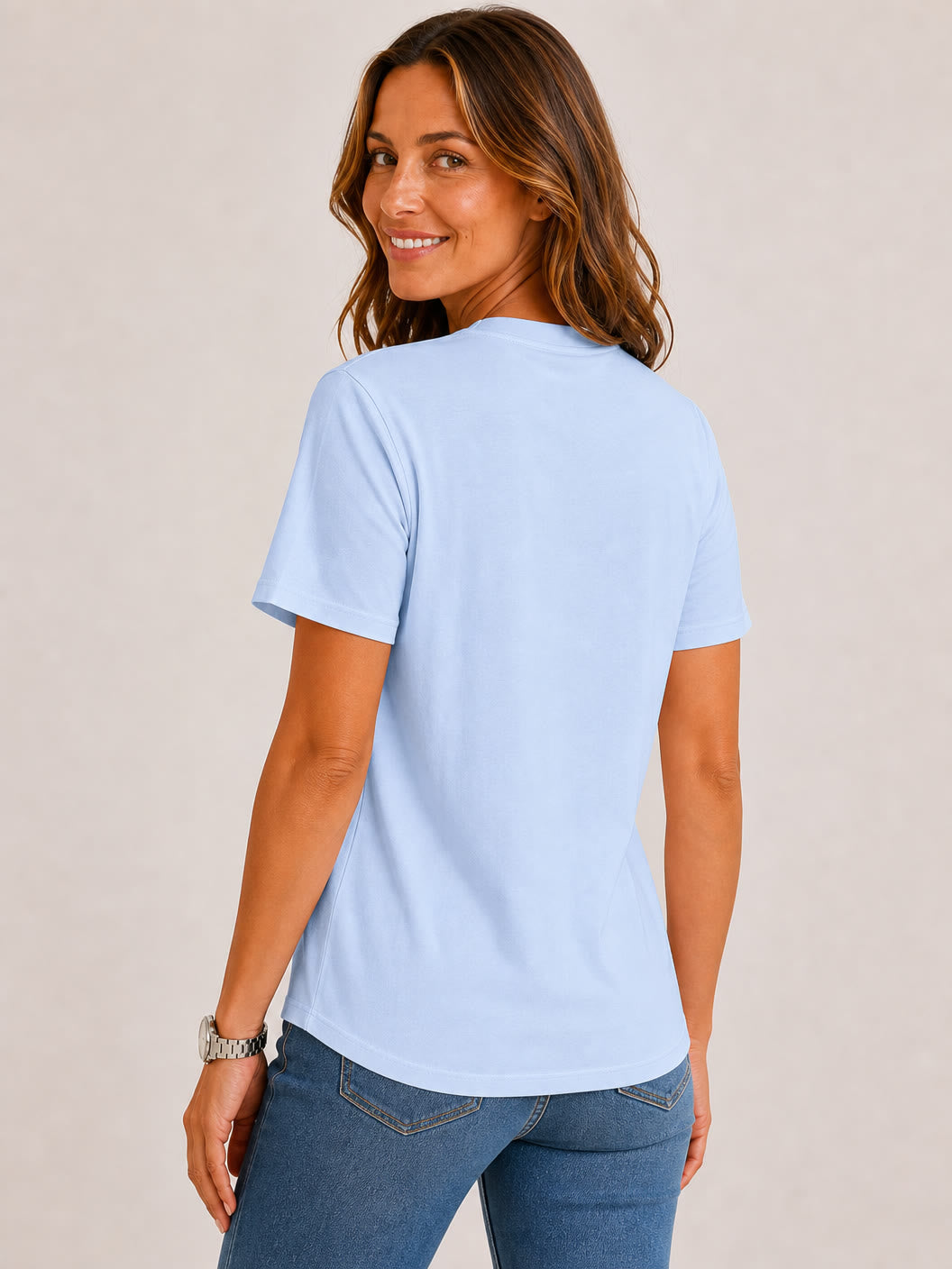 Woman wearing a light blue LoomBasics 100% cotton crew neck top and blue jeans.