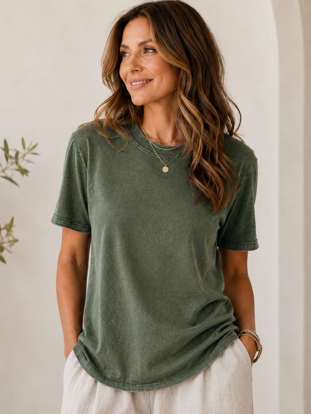 Woman wearing a LoomBasics olive green 100% cotton crew neck t-shirt and beige pants.