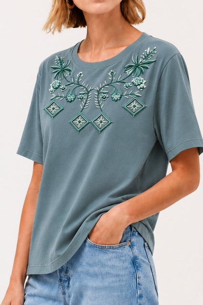 Woman wearing a LoomBasics blue cotton tee with geometric and tropical floral embroidery.