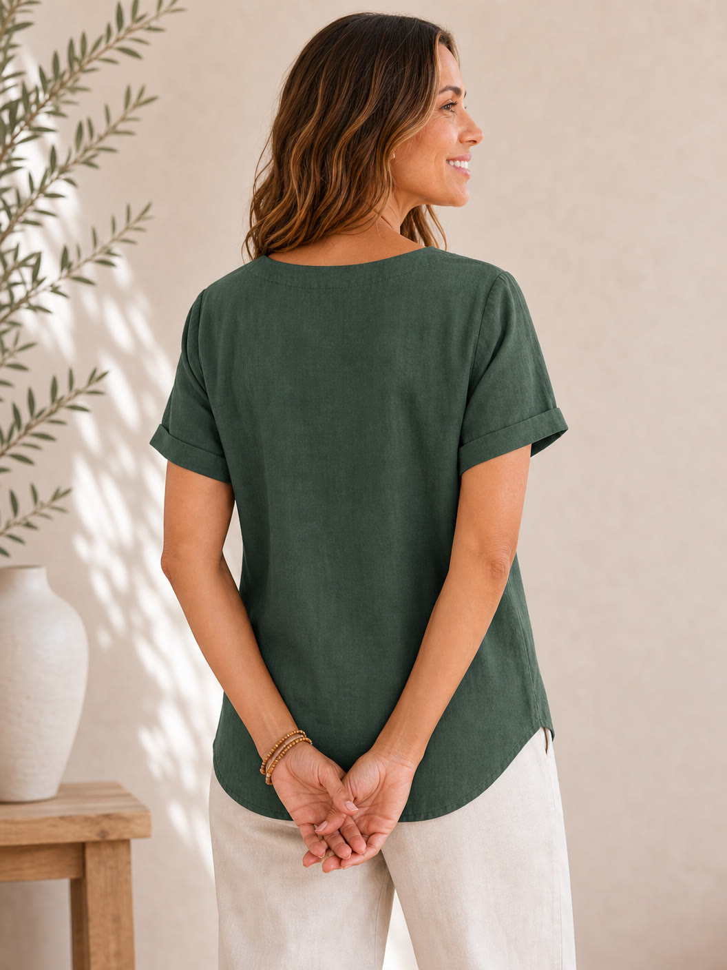 Woman wearing a LoomBasics dark green 100% cotton short-sleeve top and white pants.
