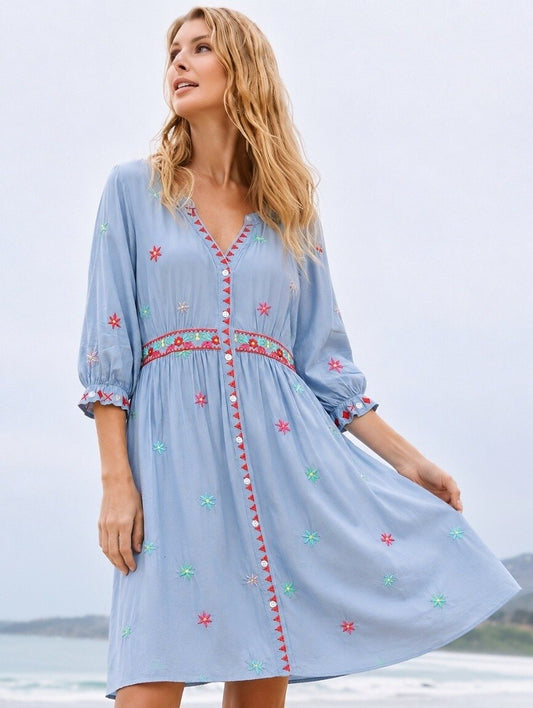 Woman wearing a light blue embroidered 100% cotton mini dress by LoomBasics on a beach.