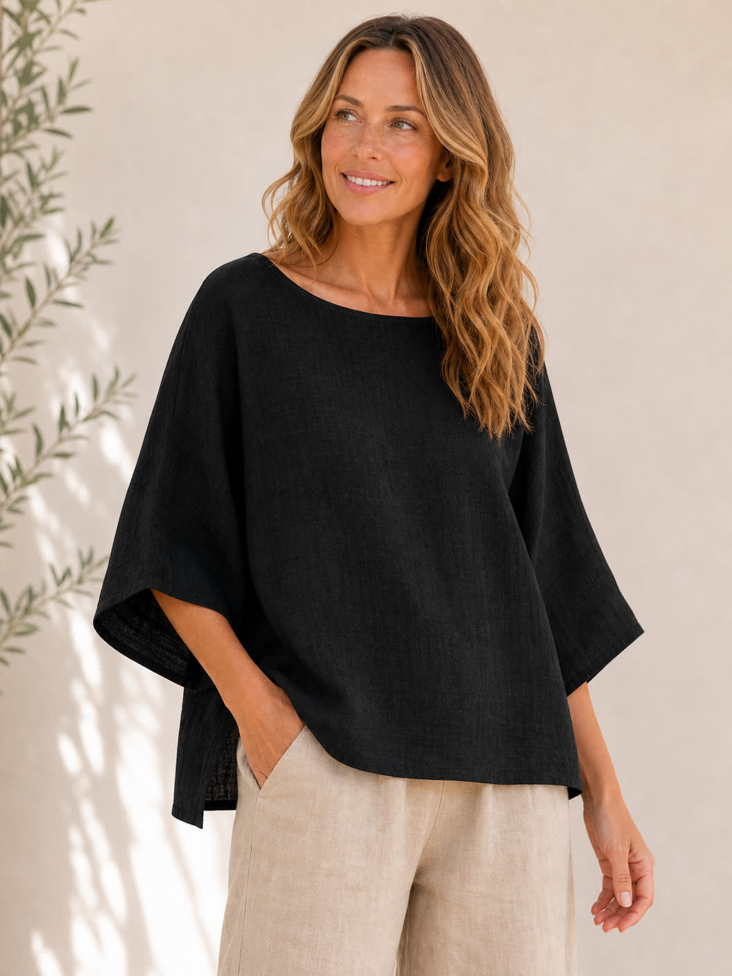 Woman wearing a LoomBasics black crew neck 100% cotton blouse and beige linen trousers.