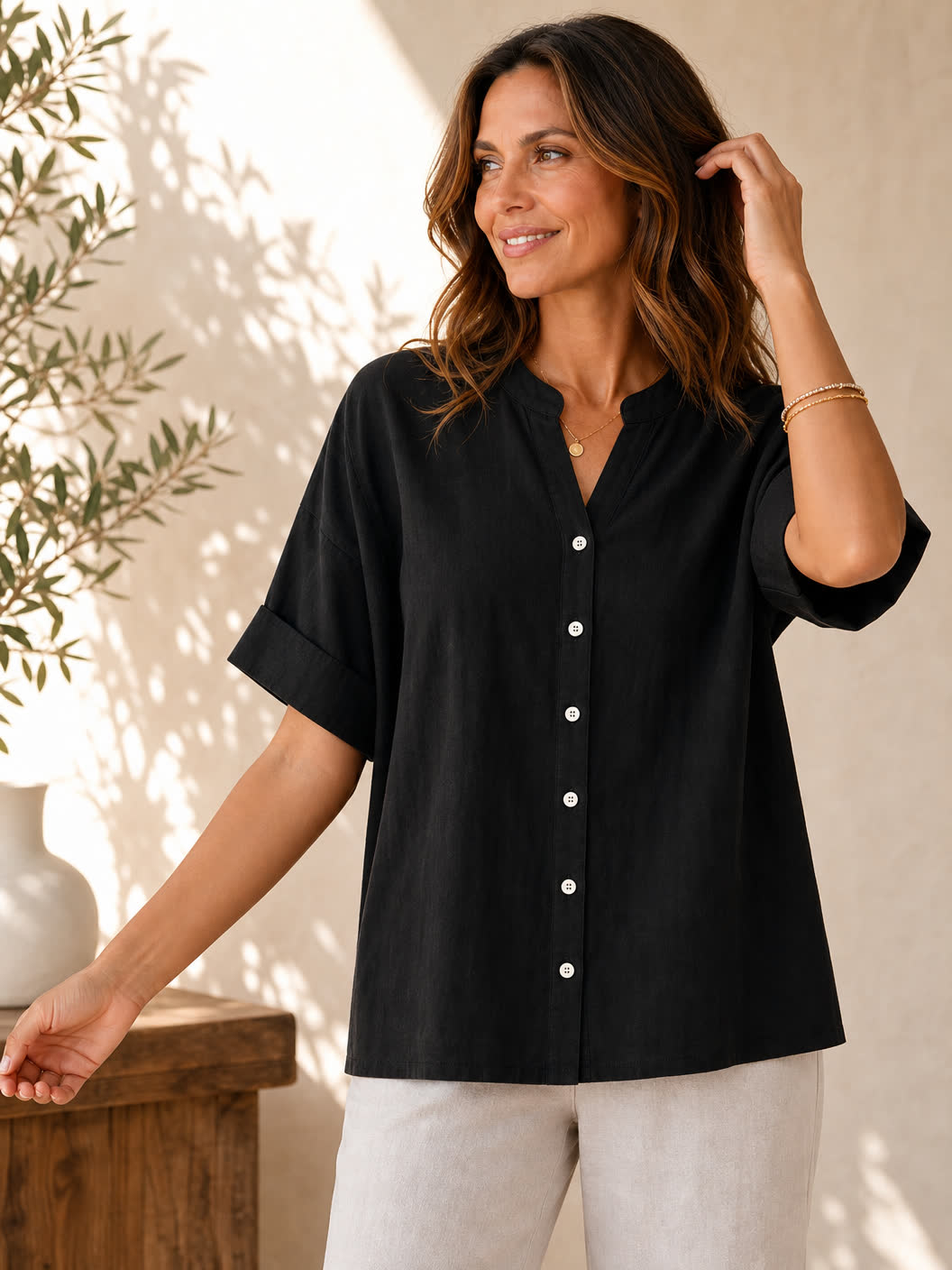 Woman wearing a black LoomBasics V neck 100% cotton blouse with white buttons.