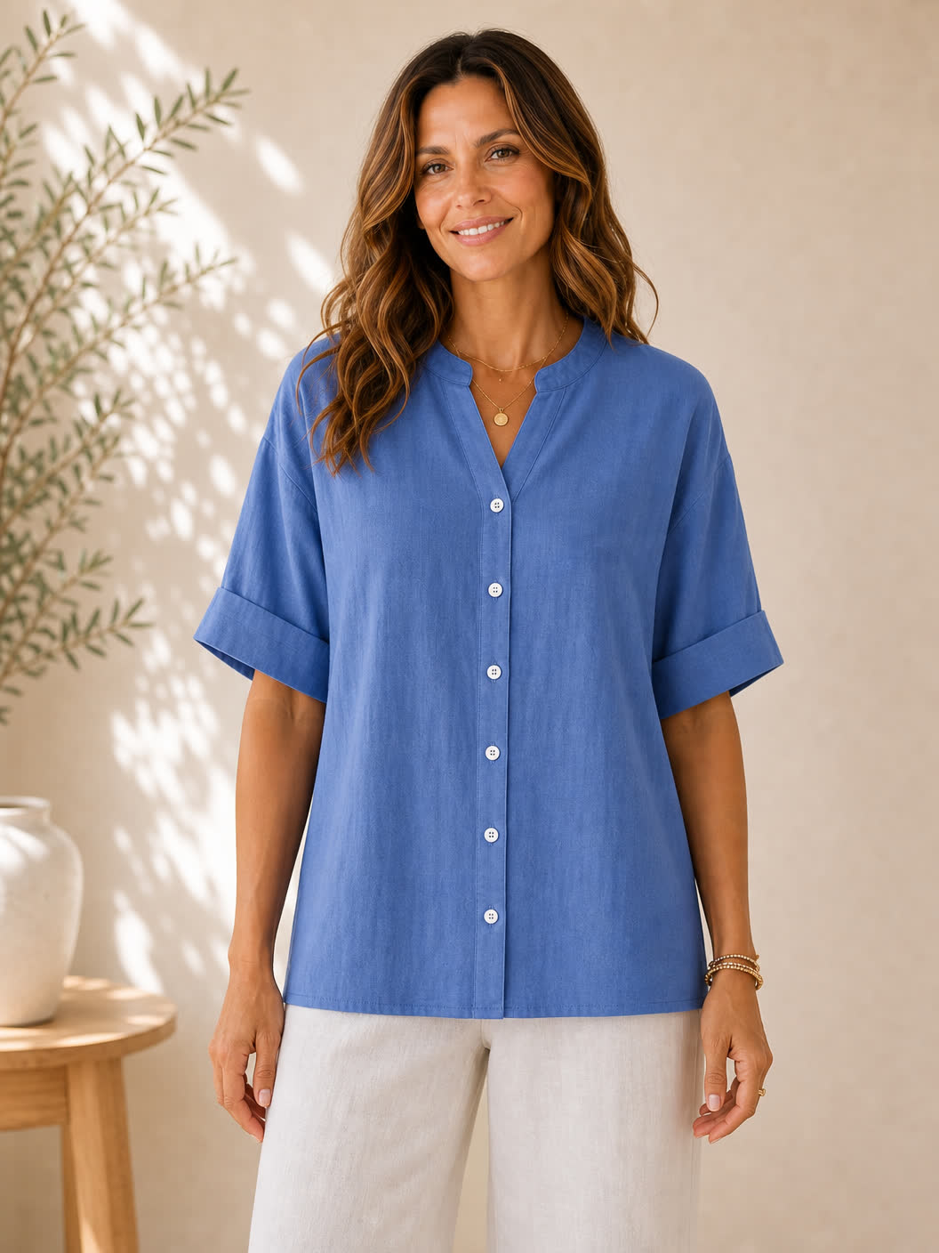 Woman wearing a blue LoomBasics V-neck 100% cotton blouse with white buttons and linen pants.