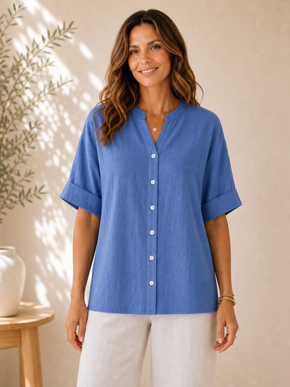 Woman wearing a blue LoomBasics V-neck 100% cotton blouse with white buttons and linen pants.