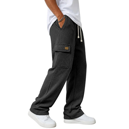 A person wearing dark charcoal gray textured cargo sweatpants with white sneakers and a white t-shirt