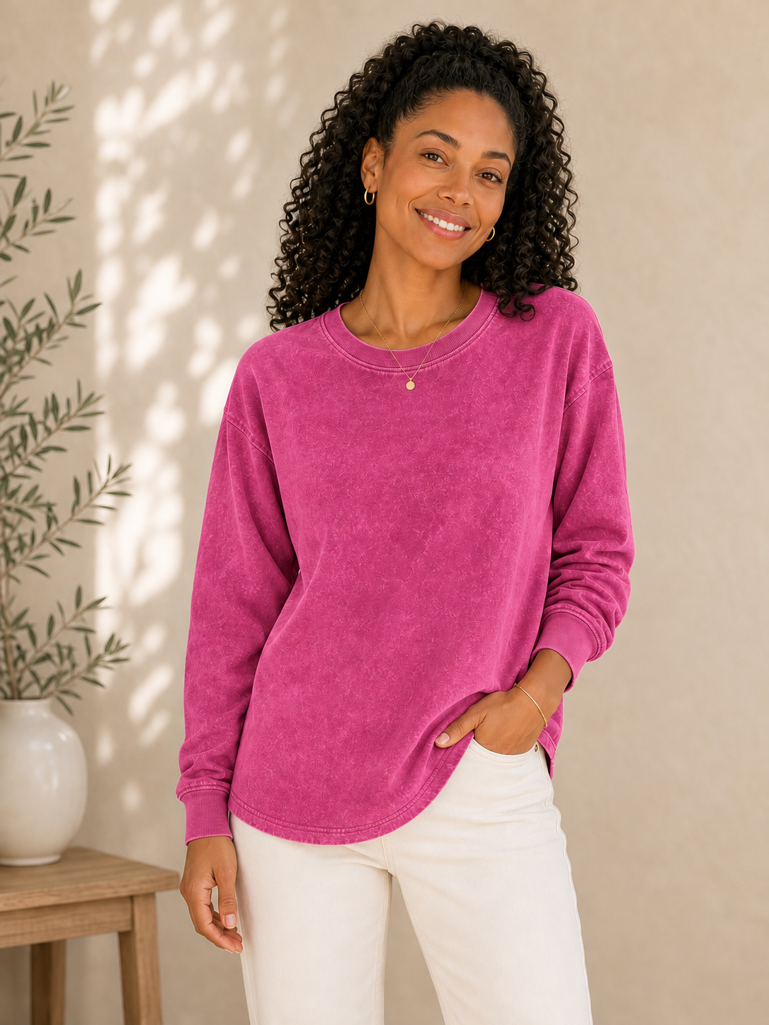 Woman wearing a magenta LoomBasics 100% cotton crewneck sweatshirt and white pants.