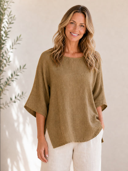 Woman wearing a LoomBasics olive green crew neck 100% cotton blouse and white pants.