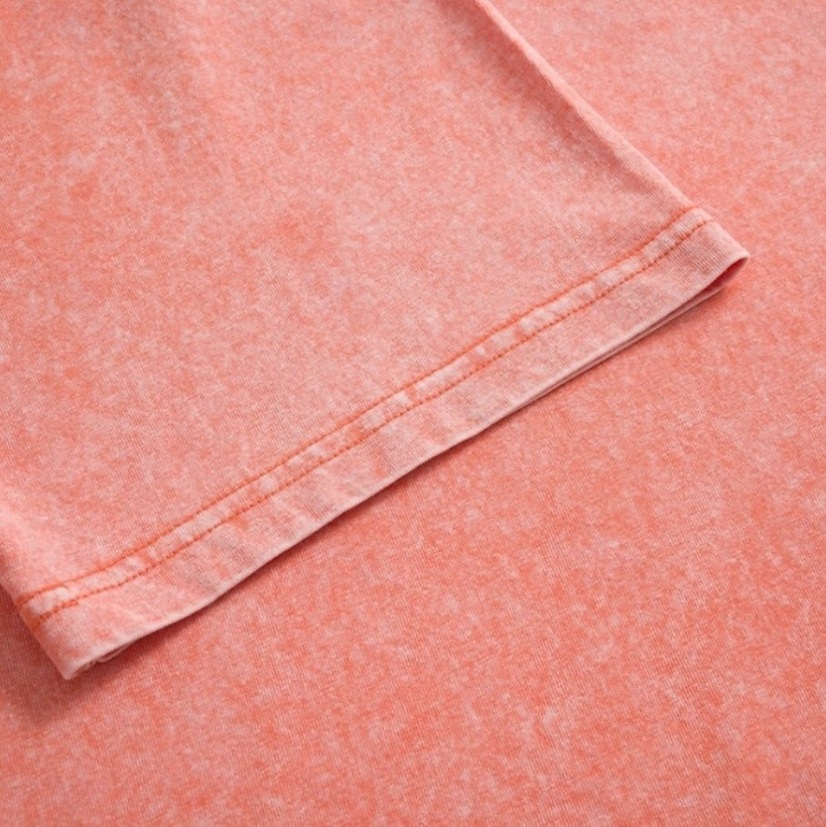 Close-up of the washed cotton fabric and stitched hem of a LoomBasics peach v-neck top.