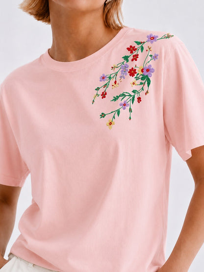 Woman wearing a LoomBasics light pink 100% cotton tee with colorful floral embroidery on the shoulder