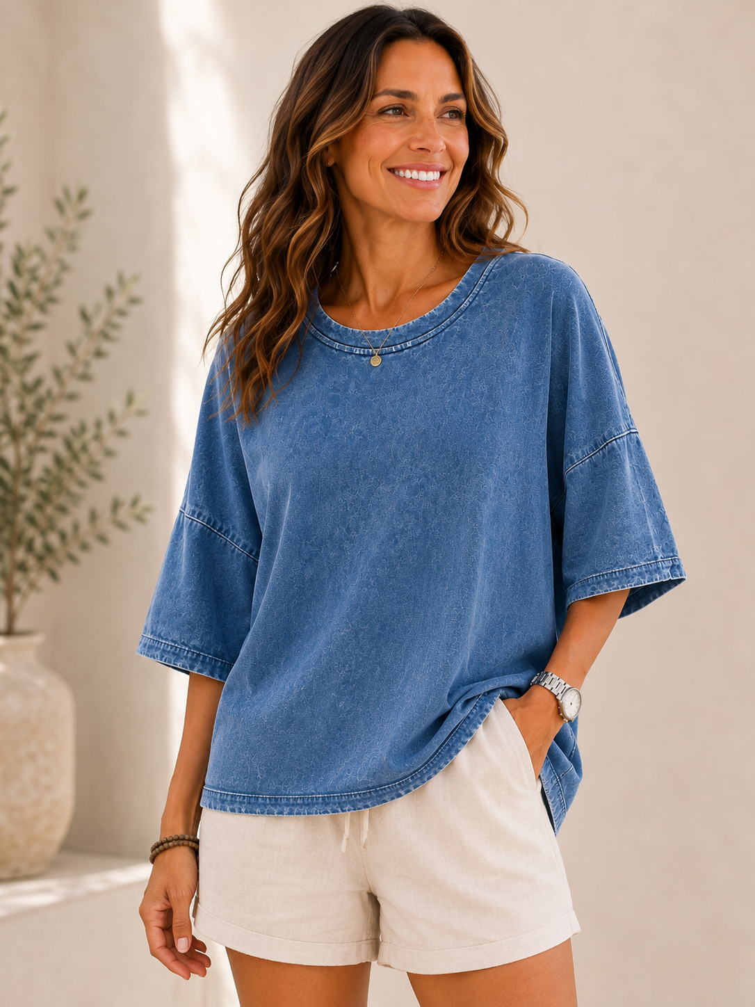 Woman wearing a LoomBasics washed blue 100% cotton blouse and beige shorts.
