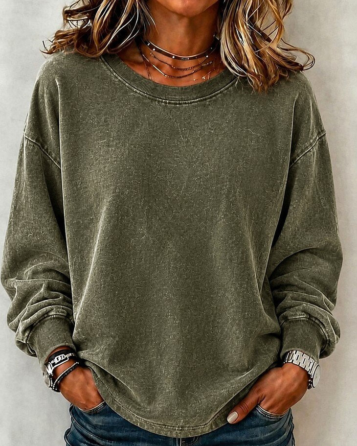Woman wearing a LoomBasics washed olive green 100% cotton crewneck sweatshirt and blue jeans.