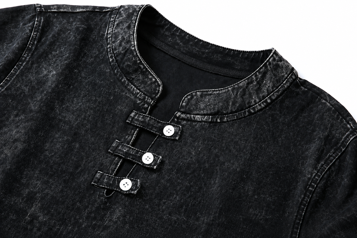 Close-up of a black 100% cotton short sleeve tee by LoomBasics with buttoned collar detail.