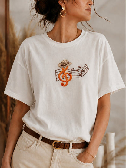 Woman wearing a white LoomBasics 100% cotton t-shirt with embroidered music note and hat design.