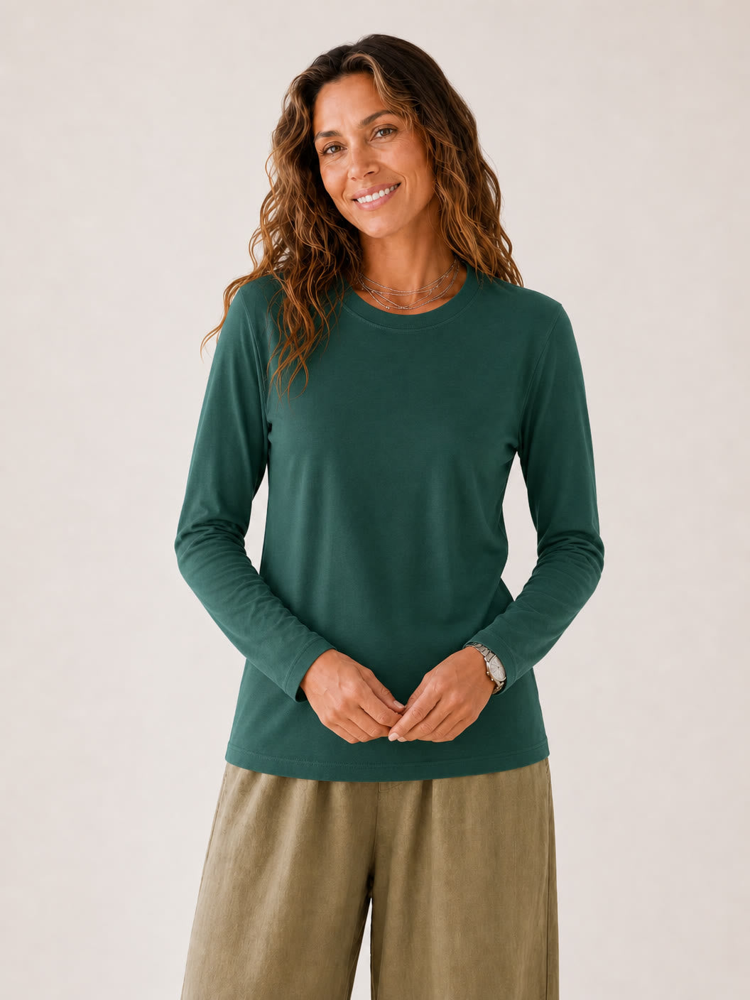 Woman wearing a LoomBasics green 100% cotton crew neck long sleeve tee and olive trousers.