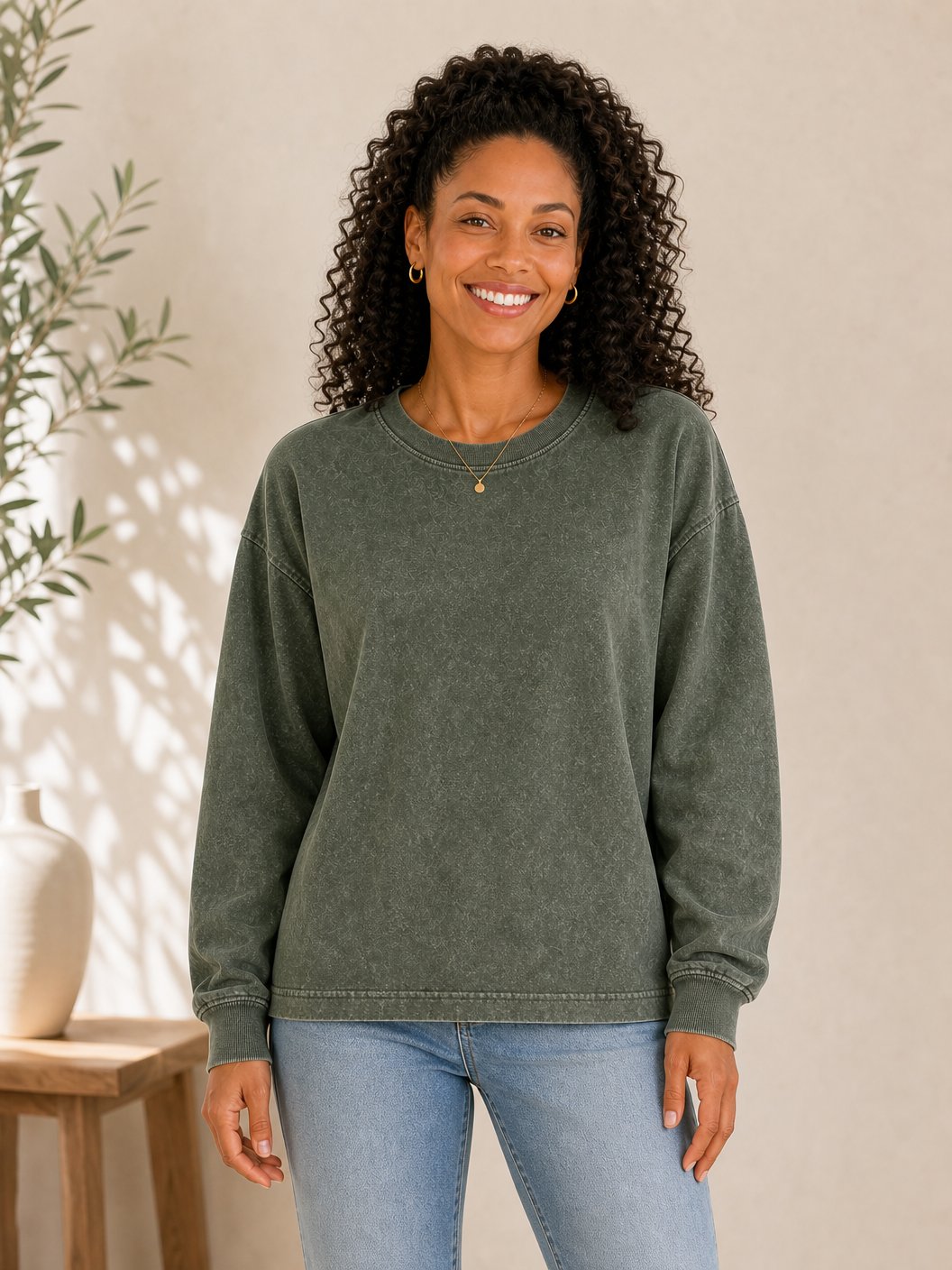 Woman wearing a LoomBasics olive green 100% cotton crewneck sweatshirt and blue jeans.