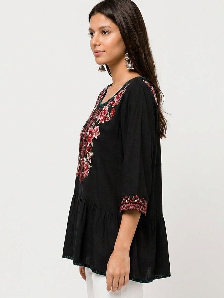 Woman wearing a black LoomBasics embroidered 100% cotton tunic shirt with floral patterns.