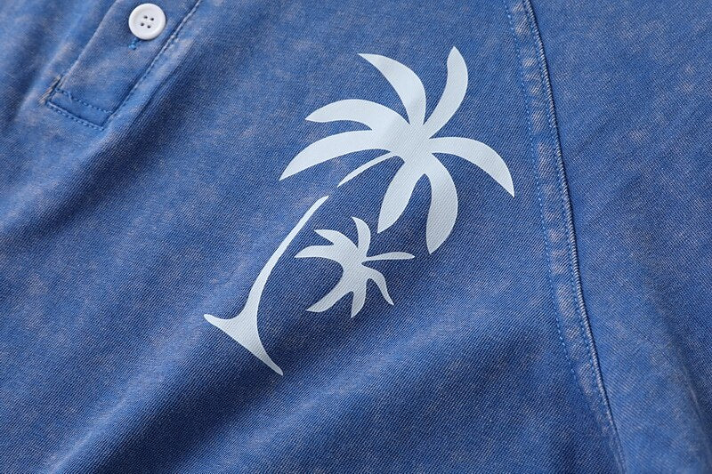 Close-up of a blue washed cotton henley tee by LoomBasics with a white palm tree print.
