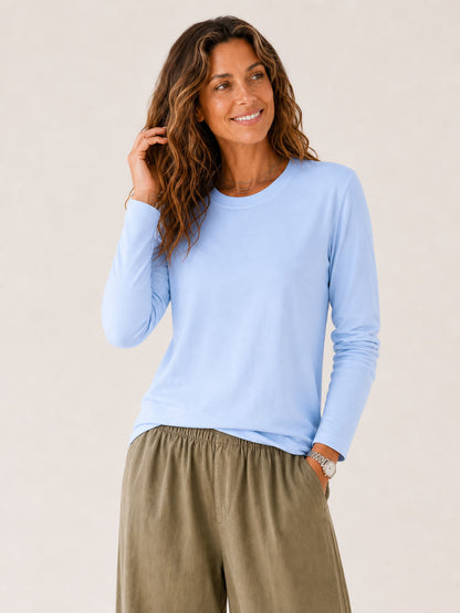 Woman wearing a LoomBasics light blue 100% cotton crew neck long sleeve tee and olive trousers.