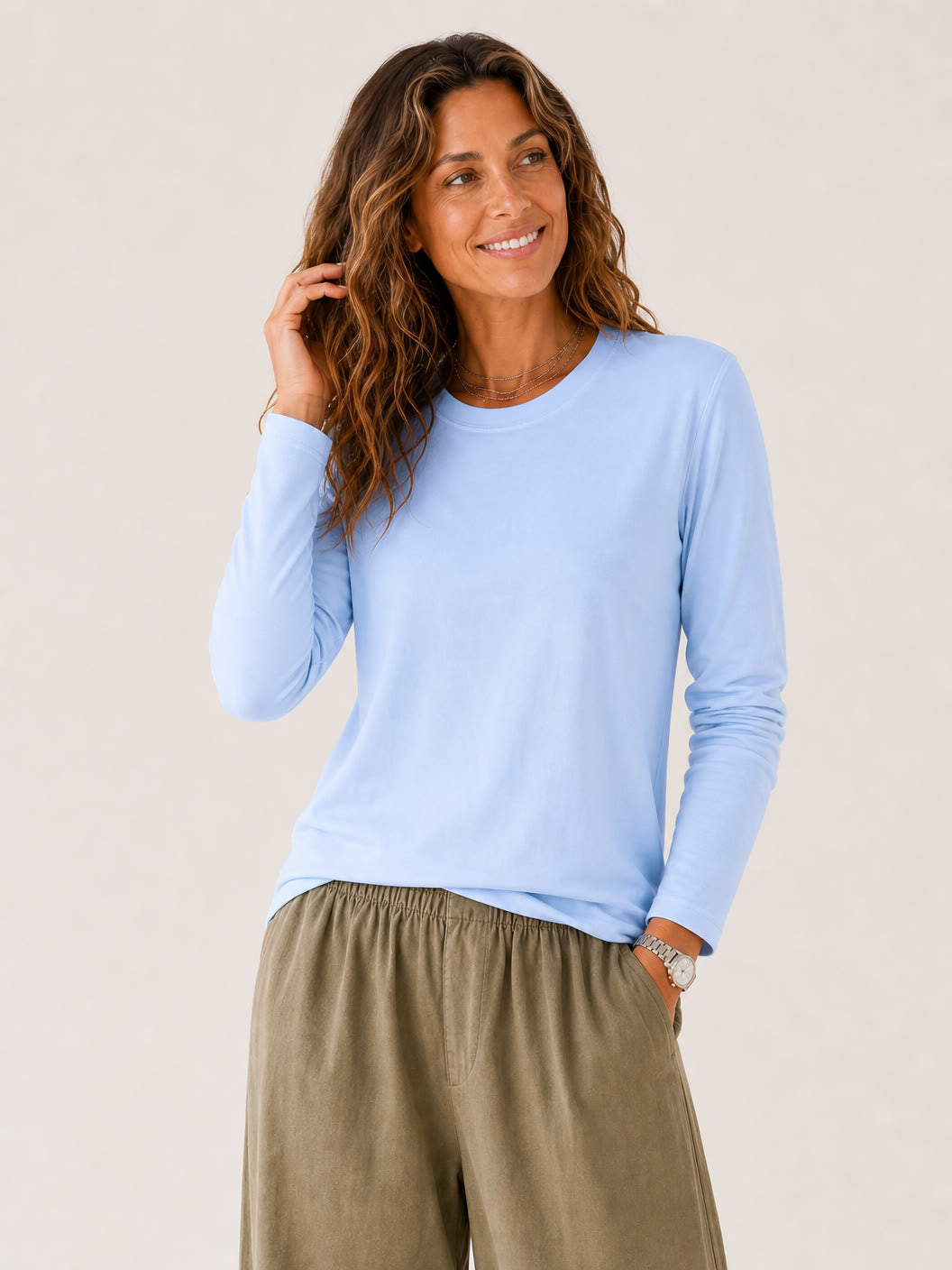 Woman wearing a LoomBasics light blue 100% cotton crew neck long sleeve tee and olive trousers.