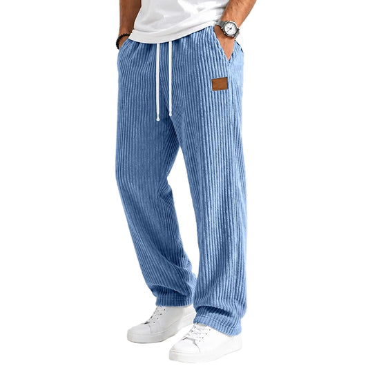 A person wearing light blue vertically striped lounge pants with a white drawstring, paired with a white t-shirt and white sneakers