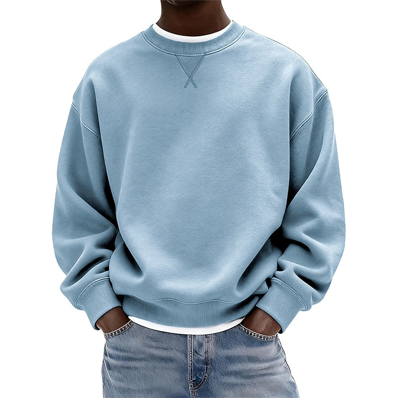 A person wearing a light blue crewneck sweatshirt with a white inner collar, paired with light blue jeans, shown from the neck down against a plain white background.