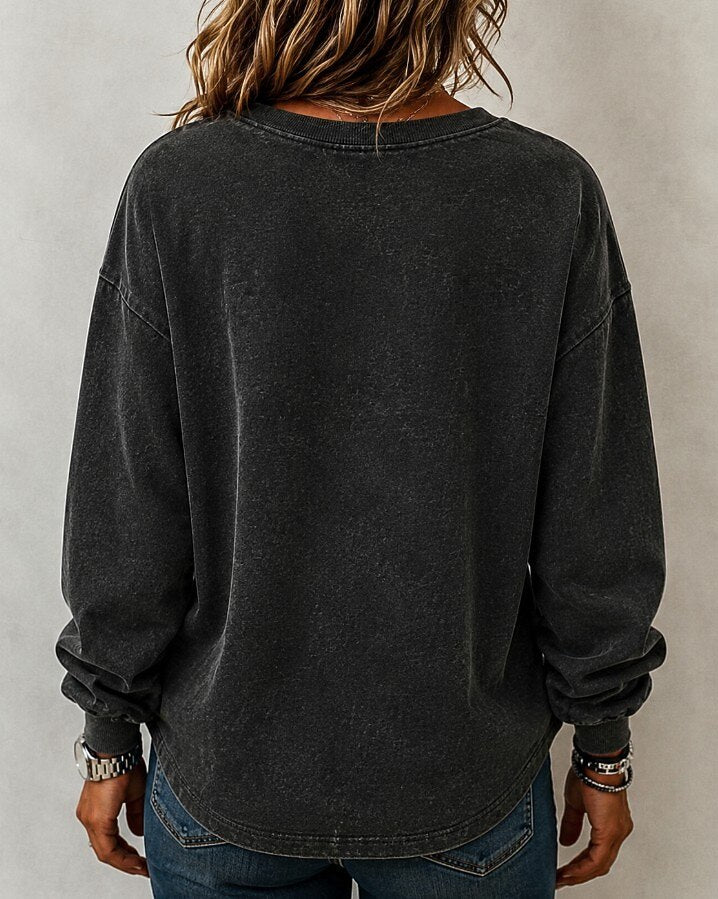 Back view of a woman wearing a LoomBasics washed dark grey cotton crewneck sweatshirt and blue jeans.