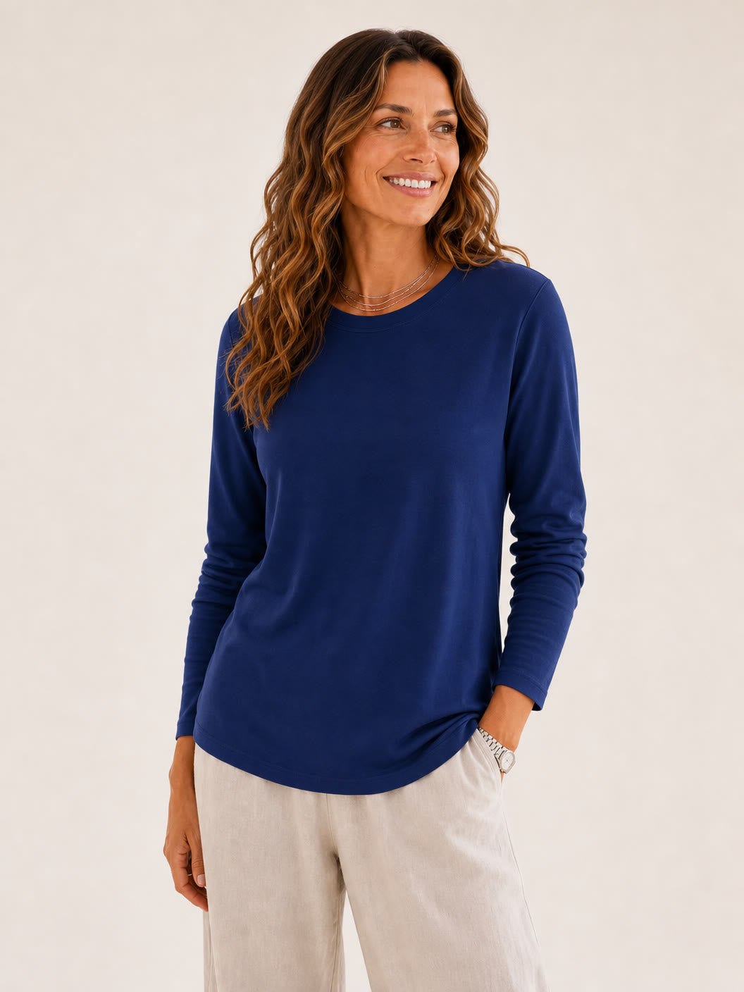 Woman wearing a LoomBasics royal blue 100% cotton crew neck long sleeve tee and beige trousers