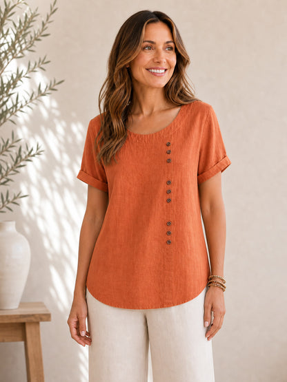 Woman wearing a rust-orange LoomBasics soft button 100% cotton blouse and white pants.