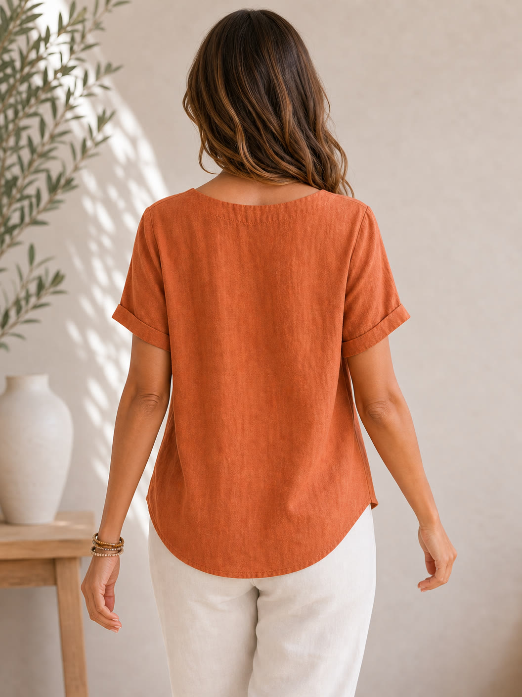 Back view of a woman wearing a LoomBasics rust-orange 100% cotton short sleeve blouse.