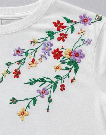 Close-up of colorful floral embroidery on a white LoomBasics 100% cotton tee.
