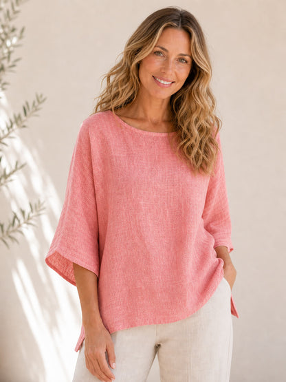 Woman wearing a pink LoomBasics crew neck 100% cotton blouse and white trousers.