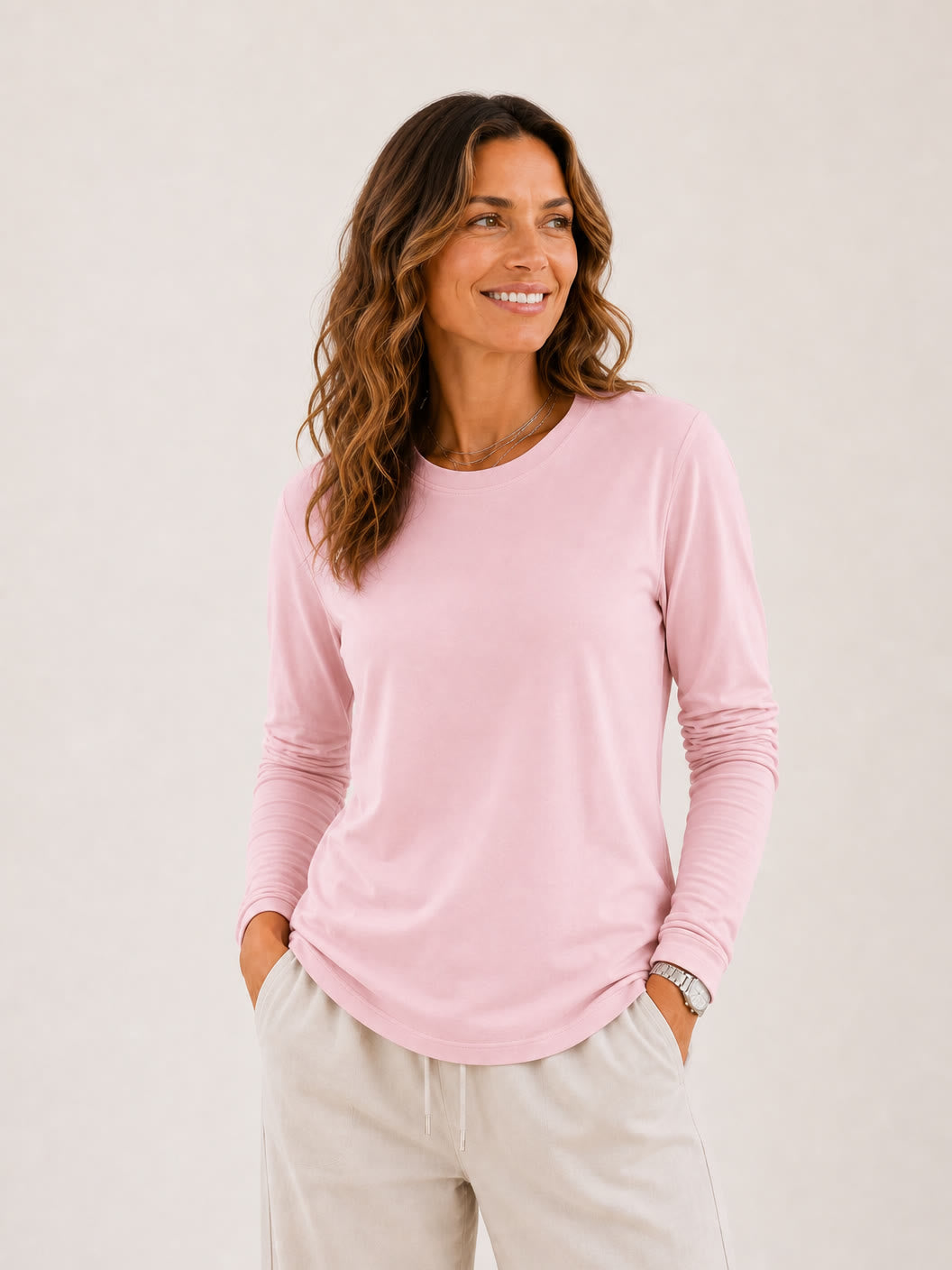 Woman wearing a pink LoomBasics 100% cotton crew neck long sleeve tee and beige lounge pants.