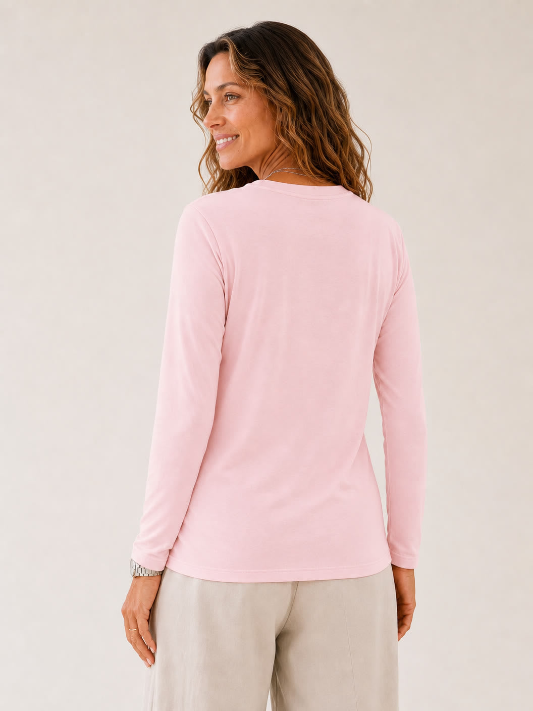 Back view of a woman wearing a LoomBasics light pink 100% cotton crew neck long sleeve tee.