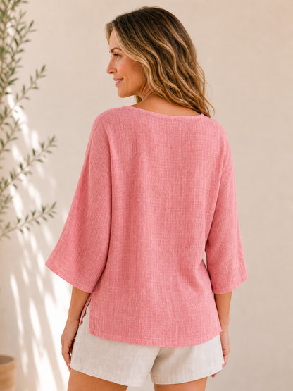 Back view of a woman wearing a pink LoomBasics crew neck 100% cotton blouse and beige shorts.
