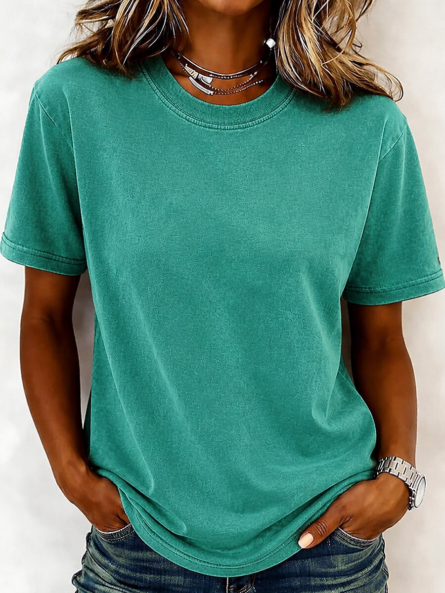 A woman wearing a teal LoomBasics 100% cotton crew neck t-shirt and blue jeans.