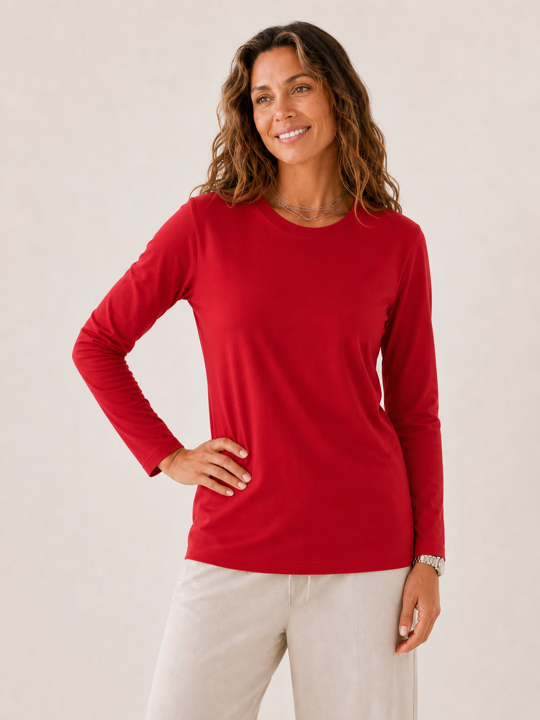 A woman wearing a red long sleeve 100% cotton crew neck tee by LoomBasics.