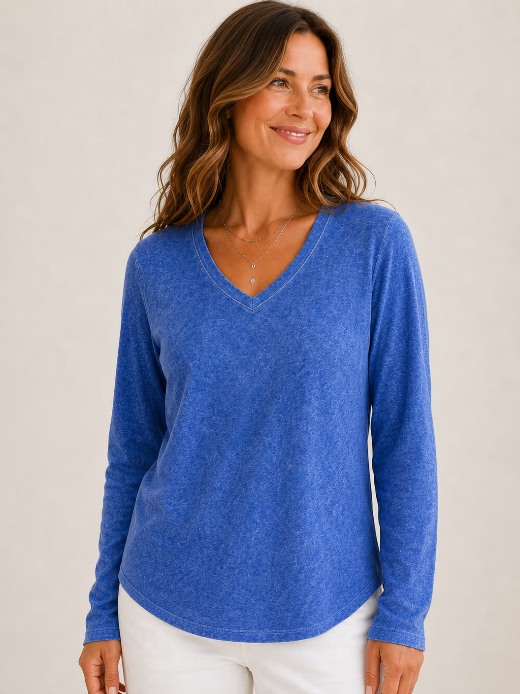 Woman wearing a LoomBasics washed 100% cotton blue v-neck long sleeve top and white pants