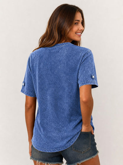 Back view of a woman wearing a LoomBasics blue 100% cotton henley shirt and denim shorts.