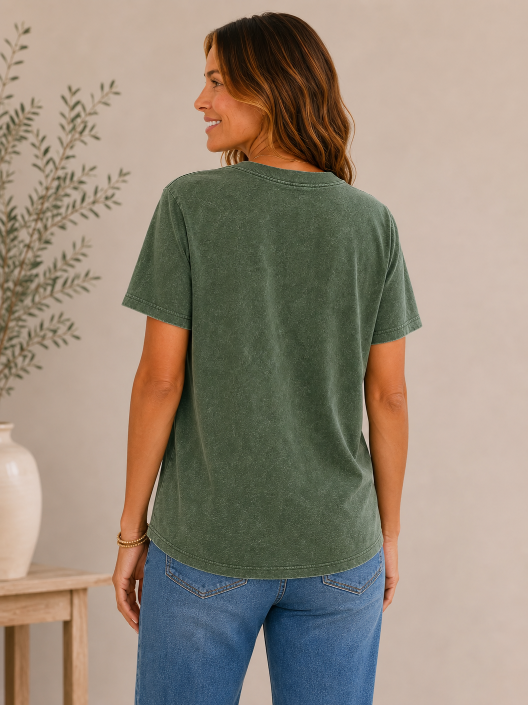 Back view of a woman wearing a LoomBasics green crew neck 100% cotton tee and blue jeans.