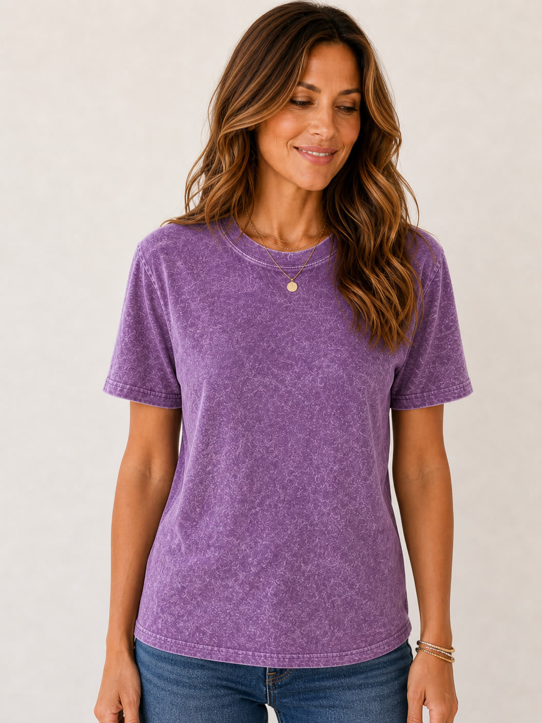 Woman wearing a LoomBasics purple mineral wash crew neck 100% cotton tee and blue jeans.