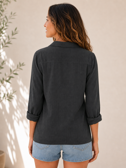 Back view of a woman wearing a LoomBasics black 100% cotton button-up shirt and denim shorts.
