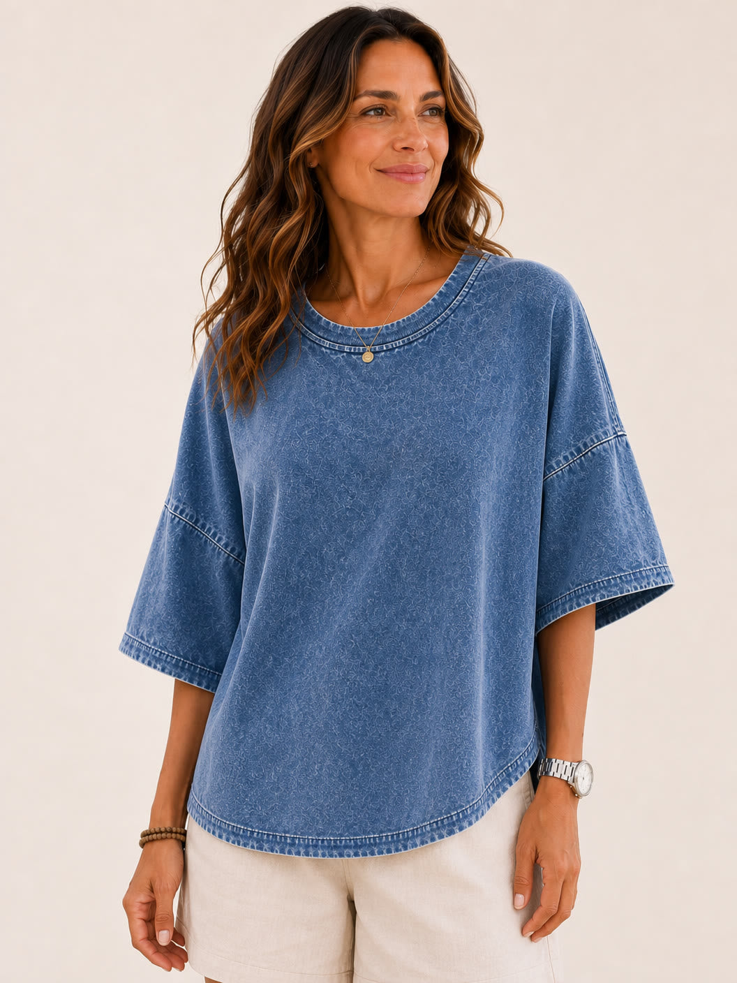 Woman wearing a LoomBasics washed blue 100% cotton blouse with beige shorts.