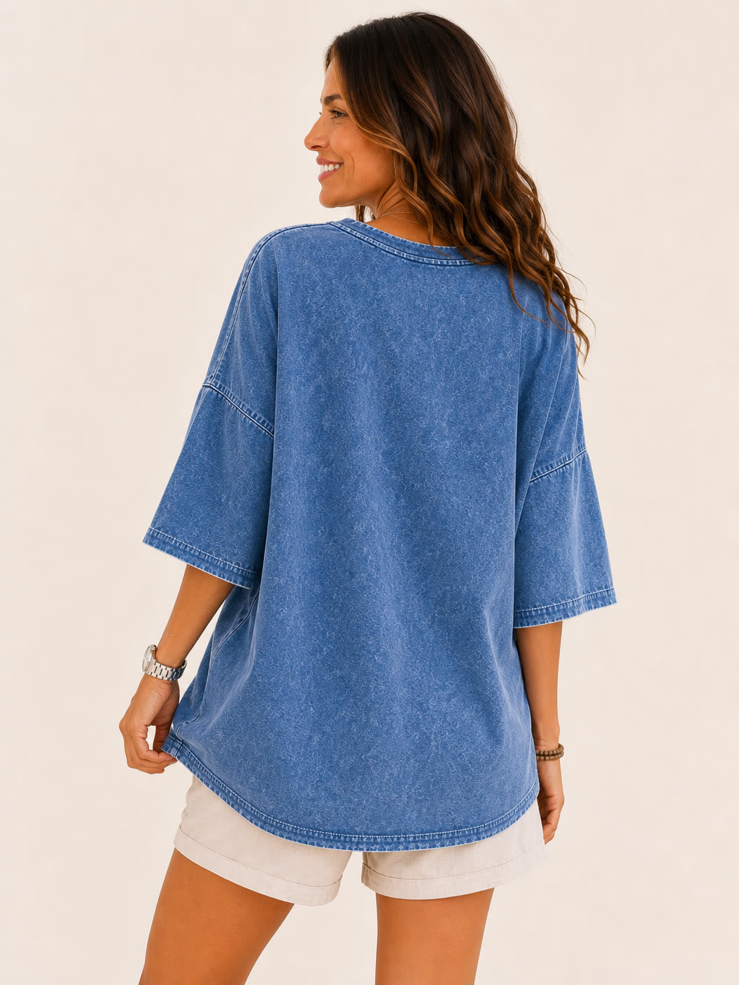 Back view of a woman wearing a LoomBasics washed blue 100% cotton oversized blouse and white shorts