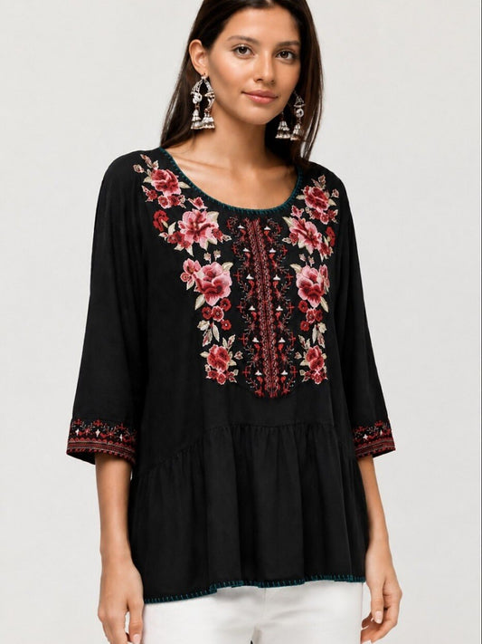 Woman wearing a black LoomBasics embroidered 100% cotton tunic shirt with red floral patterns.