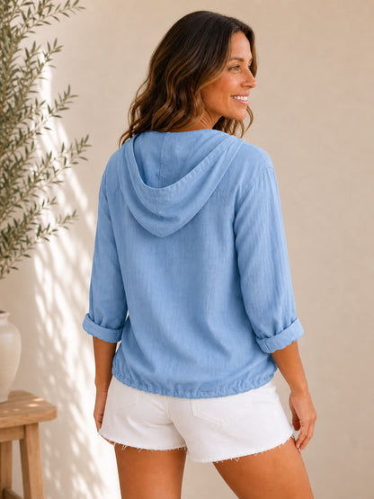 Woman wearing a LoomBasics blue 100% cotton hooded drawstring shirt and white denim shorts.