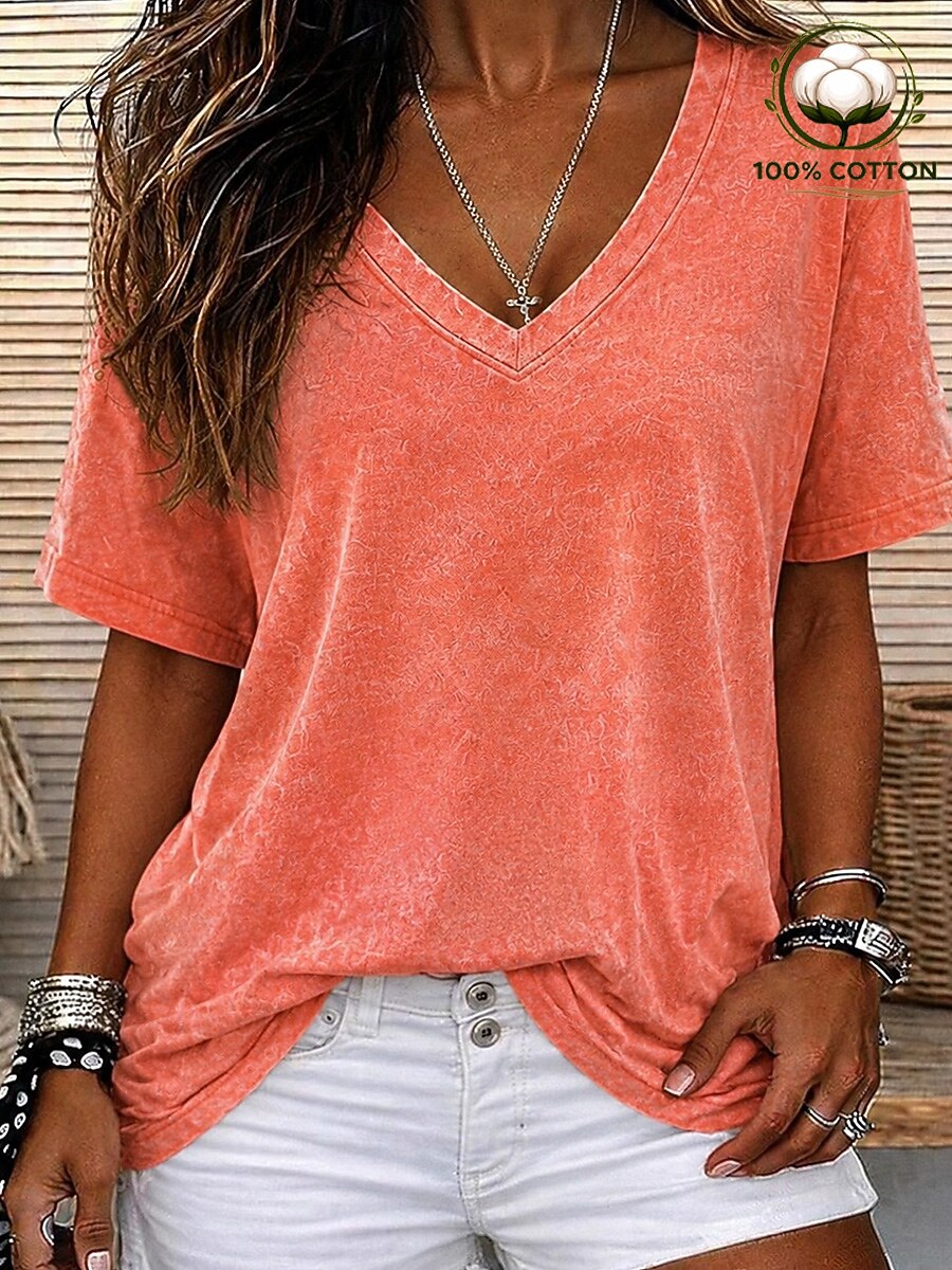 Woman wearing a LoomBasics coral pink 100% cotton V-neck tee and white denim shorts.
