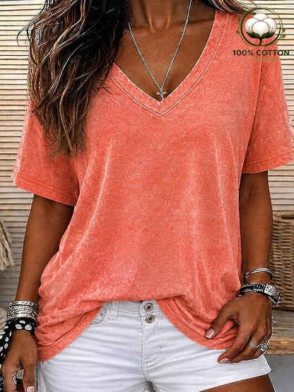 Woman wearing a LoomBasics coral pink 100% cotton V-neck tee and white denim shorts.