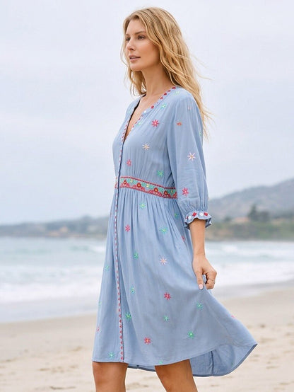 Woman wearing a LoomBasics blue embroidered 100% cotton mini dress on a sandy beach