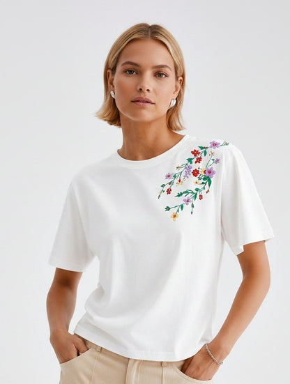 Woman wearing a LoomBasics white 100% cotton t-shirt with colorful floral embroidery on the shoulder
